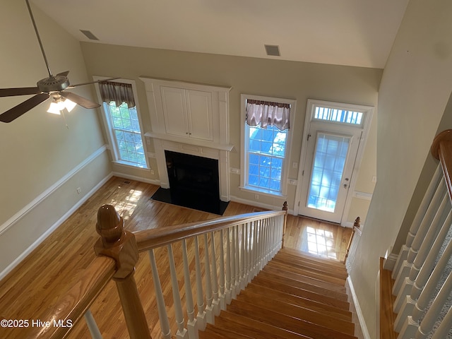 unfurnished living room with lofted ceiling, hardwood / wood-style floors, a premium fireplace, a ceiling fan, and baseboards