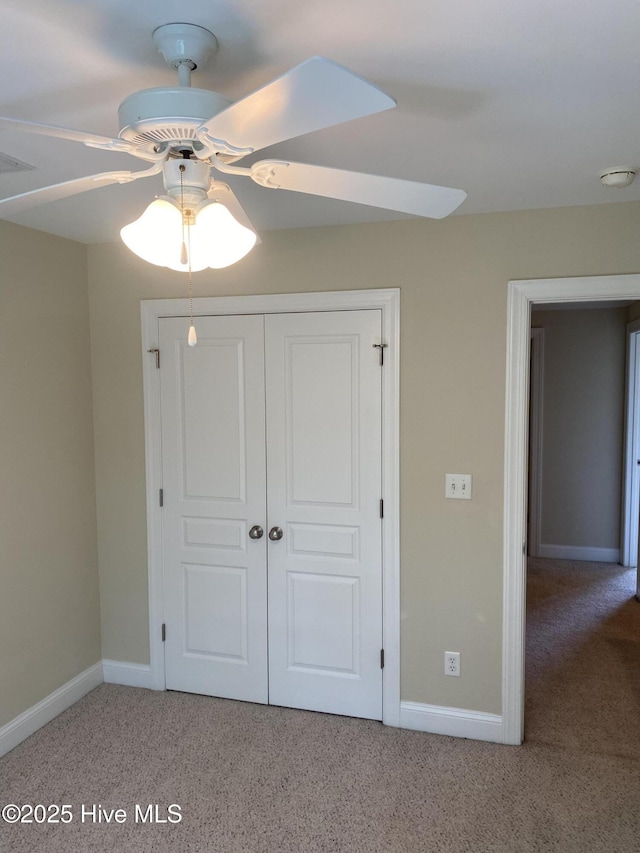 unfurnished bedroom with light colored carpet, a closet, baseboards, and a ceiling fan
