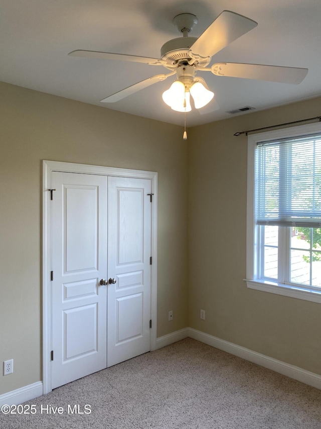 unfurnished bedroom featuring baseboards, light carpet, a closet, and ceiling fan