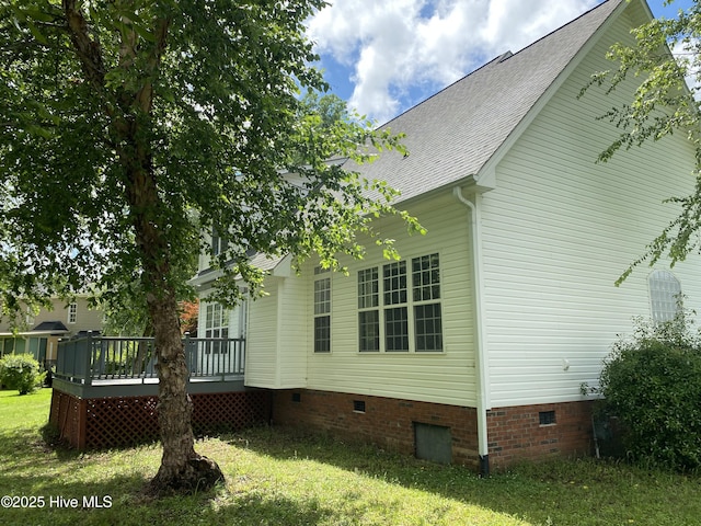 view of home's exterior featuring crawl space, roof with shingles, a deck, and a lawn