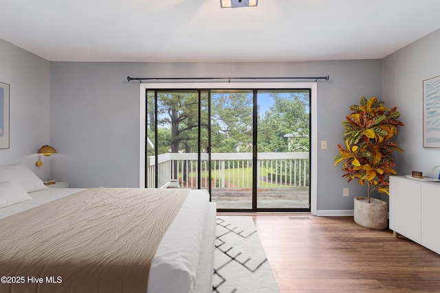 bedroom with access to outside, wood finished floors, and baseboards