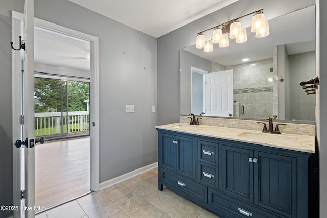bathroom with a stall shower, baseboards, and double vanity