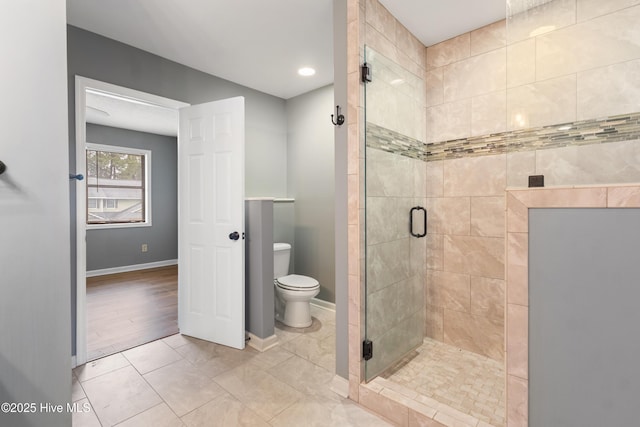 bathroom featuring a stall shower, toilet, baseboards, and tile patterned flooring