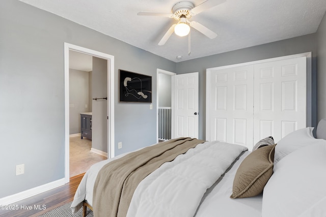 bedroom with a closet, wood finished floors, baseboards, a ceiling fan, and ensuite bathroom