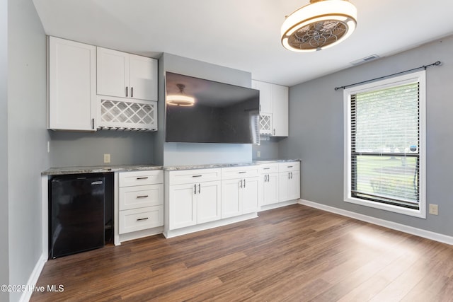 kitchen featuring dark wood-type flooring, baseboards, wine cooler, white cabinets, and light stone counters