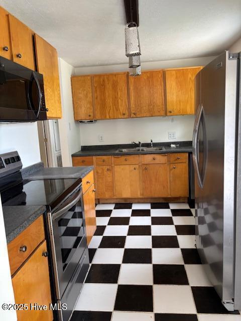6007 Meadow Ln, Goldsboro, NC 27530 - kitchen featuring stainless steel appliances, tile patterned floors, a sink, dark countertops, and brown cabinets