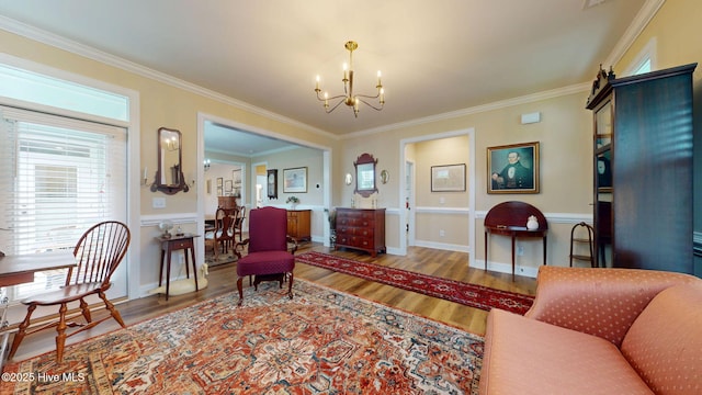 living area with wood finished floors, a chandelier, crown molding, and baseboards