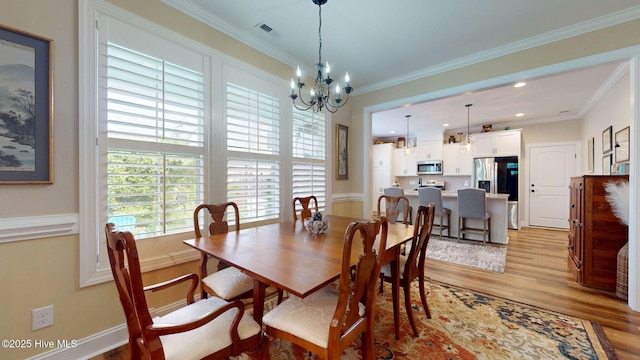 dining area with a chandelier, light wood-style floors, ornamental molding, and recessed lighting