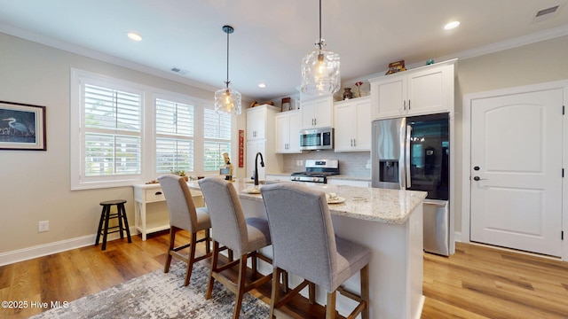 kitchen featuring appliances with stainless steel finishes, backsplash, crown molding, a kitchen breakfast bar, and light wood finished floors