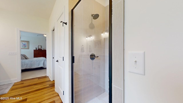 bathroom featuring a shower stall, connected bathroom, and wood finished floors