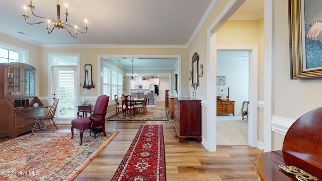 hallway featuring a chandelier, wood finished floors, ornamental molding, and baseboards
