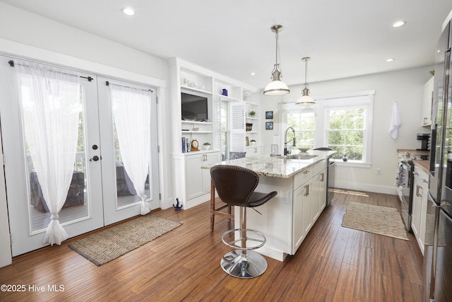 297 Broad St, Oriental, NC 28571 - kitchen featuring a sink, white cabinetry, an island with sink, light stone counters, and dark wood finished floors