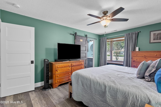 205 Sand Dollar Ln, Hampstead, NC 28443 - bedroom featuring a textured ceiling, wood finished floors, baseboards, a ceiling fan, and a barn door