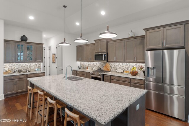 3752 Glenmere Ln, Southport, NC 28461 - kitchen featuring appliances with stainless steel finishes, a sink, backsplash, a kitchen island with sink, and a breakfast bar