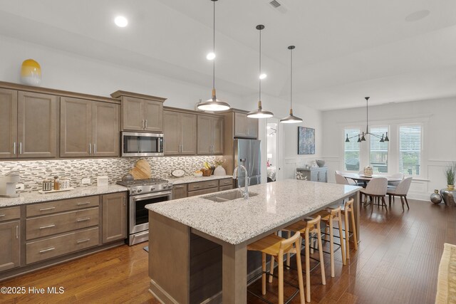3752 Glenmere Ln, Southport, NC 28461 - kitchen with appliances with stainless steel finishes, a sink, a kitchen bar, a decorative wall, and tasteful backsplash