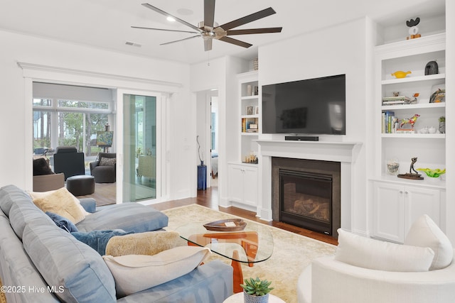 3752 Glenmere Ln, Southport, NC 28461 - living room featuring ceiling fan, wood finished floors, built in shelves, and a glass covered fireplace