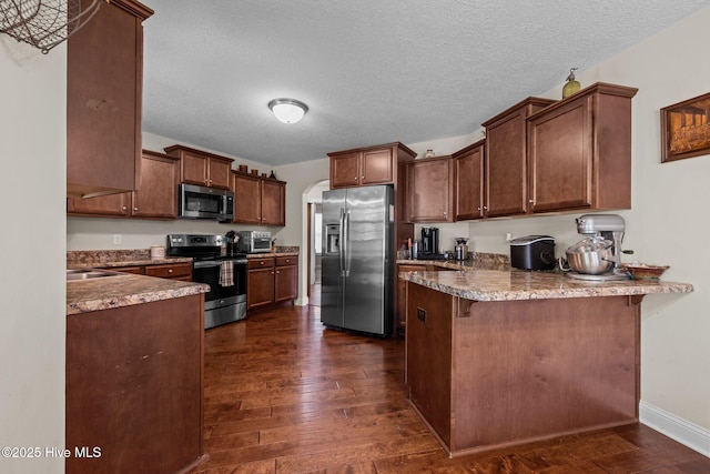 606 Spoleto Ct, Swansboro, NC 28584 - kitchen with stainless steel appliances, a peninsula, dark wood-type flooring, a textured ceiling, and a sink