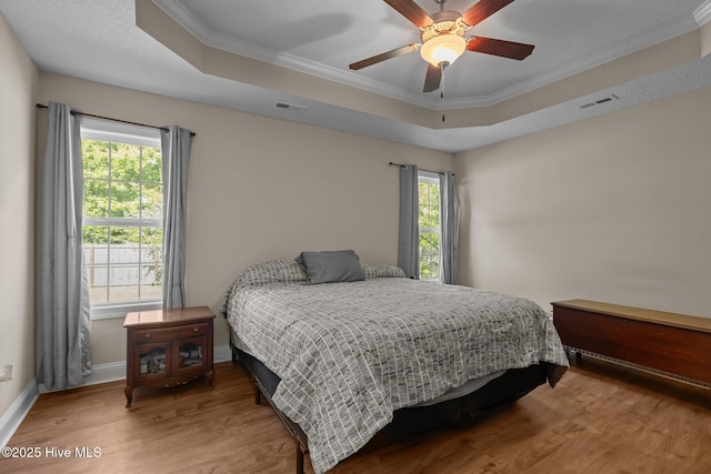 606 Spoleto Ct, Swansboro, NC 28584 - bedroom featuring a tray ceiling, wood finished floors, multiple windows, crown molding, and a ceiling fan
