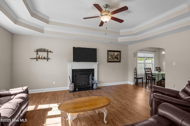 606 Spoleto Ct, Swansboro, NC 28584 - living room with arched walkways, a raised ceiling, ornamental molding, a ceiling fan, and wood finished floors