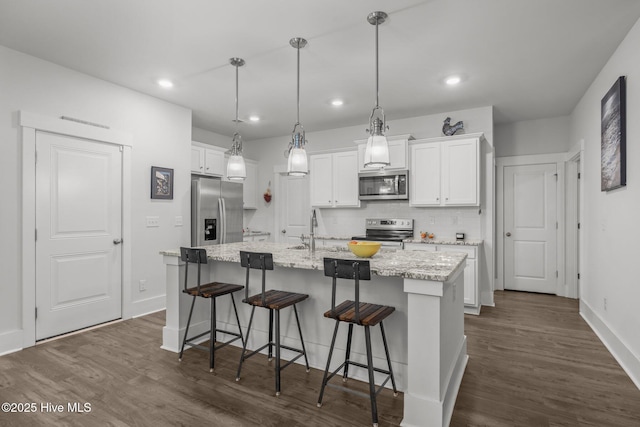 kitchen with stainless steel appliances, a sink, white cabinetry, a kitchen island with sink, and recessed lighting