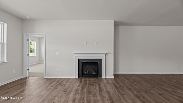 unfurnished living room with wood finished floors, a fireplace, and baseboards