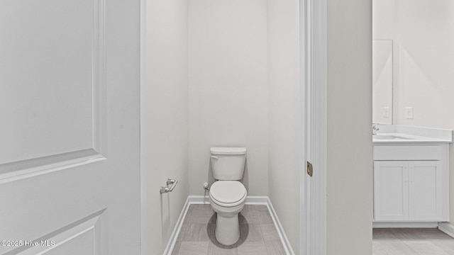 bathroom featuring toilet, vanity, baseboards, and tile patterned floors