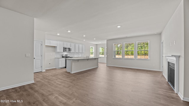 kitchen featuring appliances with stainless steel finishes, open floor plan, recessed lighting, light wood-type flooring, and white cabinets