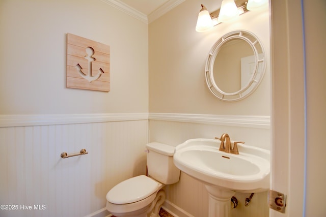 half bath with wainscoting, toilet, and ornamental molding