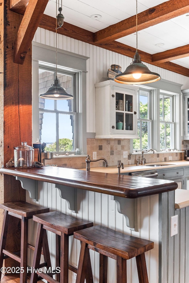21 Sea Gull Trl, Bald Head Island, NC 28461 - kitchen featuring a sink, tasteful backsplash, beamed ceiling, healthy amount of natural light, and decorative light fixtures