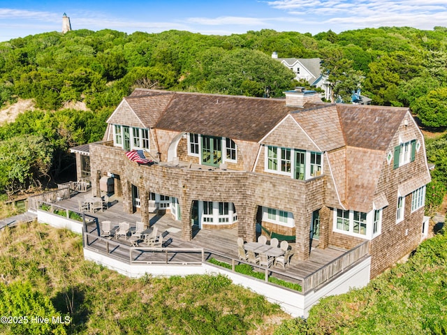 21 Sea Gull Trl, Bald Head Island, NC 28461 - back of property with a gambrel roof, a forest view, a deck, a chimney, and a shingled roof