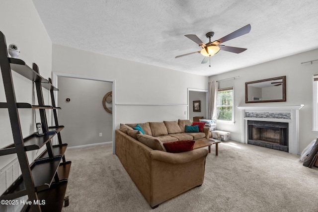 carpeted living room featuring a ceiling fan, a textured ceiling, and a fireplace