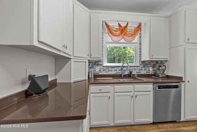 kitchen featuring dishwasher, a sink, white cabinetry, and tasteful backsplash