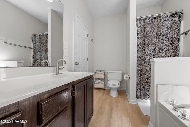 full bath with wood finished floors, toilet, vanity, curtained shower, and baseboards