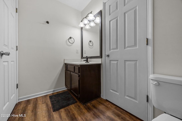 bathroom with toilet, wood finished floors, vanity, and baseboards