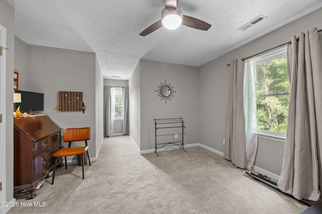living area featuring a textured ceiling, carpet flooring, ceiling fan, and baseboards