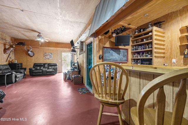 bar with wood walls, finished concrete flooring, and a ceiling fan