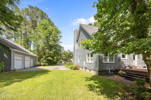 view of green lawn with a wooden deck and a detached garage