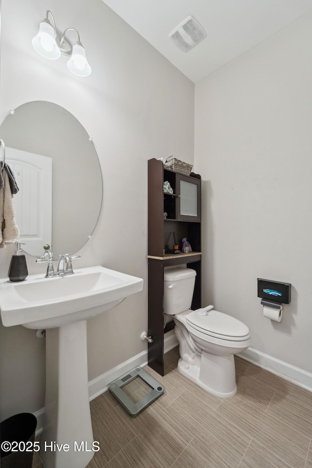 half bathroom with toilet, baseboards, and a sink