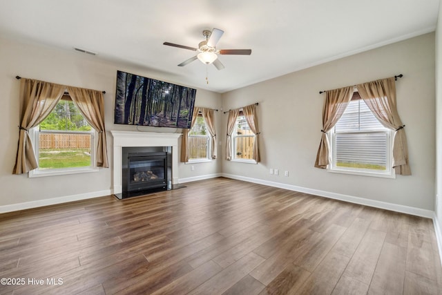 unfurnished living room featuring a ceiling fan, wood finished floors, a glass covered fireplace, and baseboards