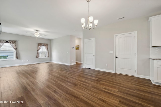 unfurnished living room featuring ceiling fan, dark wood-type flooring, a chandelier, and baseboards