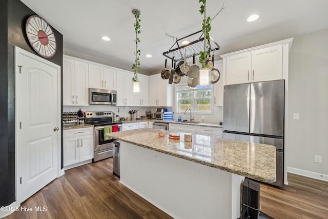 kitchen with appliances with stainless steel finishes, a sink, dark wood finished floors, white cabinetry, and recessed lighting