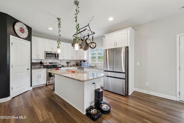 kitchen with appliances with stainless steel finishes, dark wood-style floors, white cabinetry, recessed lighting, and a kitchen island