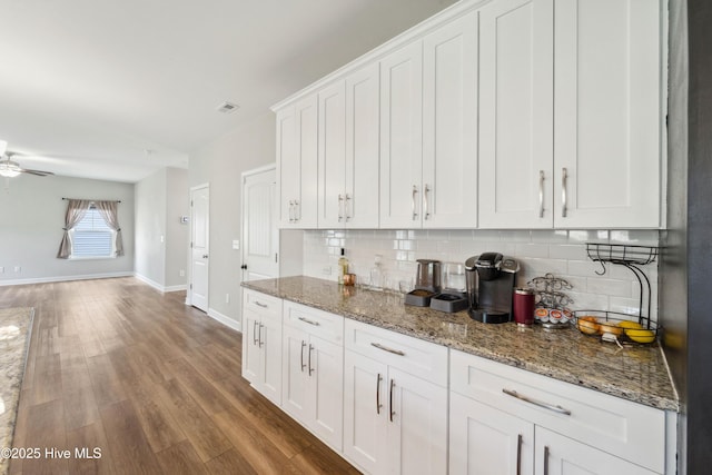 kitchen with backsplash, white cabinetry, and light stone countertops