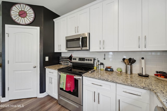 kitchen with appliances with stainless steel finishes, wood finished floors, decorative backsplash, and white cabinets