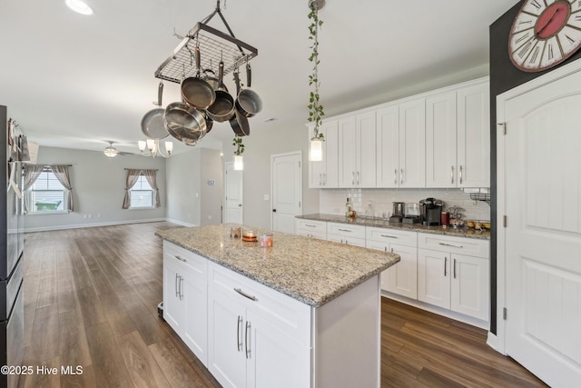kitchen with dark wood finished floors, a center island, backsplash, open floor plan, and white cabinetry