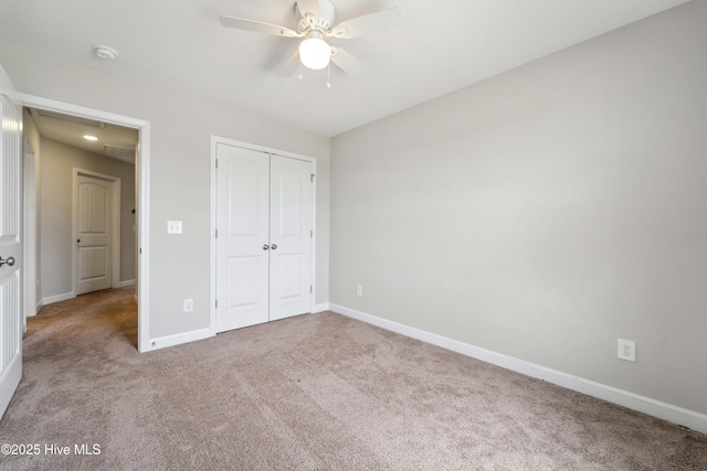 unfurnished bedroom with carpet, attic access, baseboards, and a closet