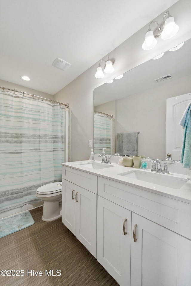 full bathroom featuring toilet, double vanity, wood tiled floors, and recessed lighting