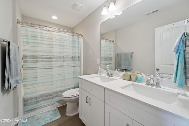 full bathroom featuring toilet, double vanity, and wood finished floors