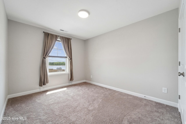 spare room featuring carpet flooring and baseboards