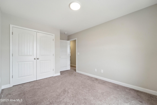 unfurnished bedroom featuring carpet, a closet, and baseboards